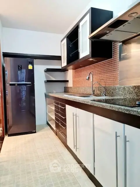 Modern kitchen with sleek cabinets, granite countertops, and stainless steel appliances in a stylish apartment.