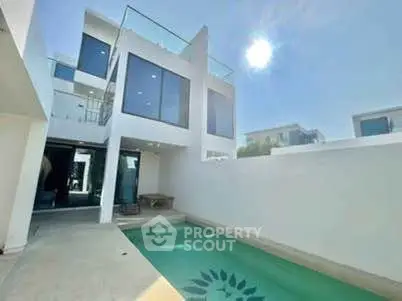 Modern white villa with private pool and large windows under clear blue sky.