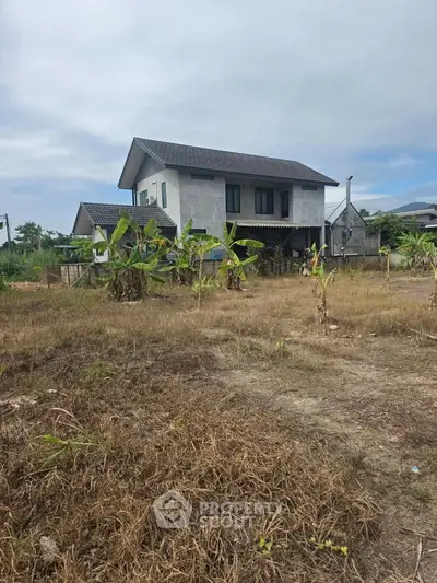 Charming two-story house with spacious yard and lush greenery, perfect for serene living.