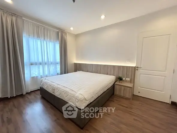 Spacious bedroom with modern design and large window offering natural light