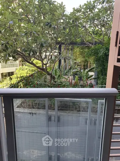 Lush garden view from a modern balcony with glass railing