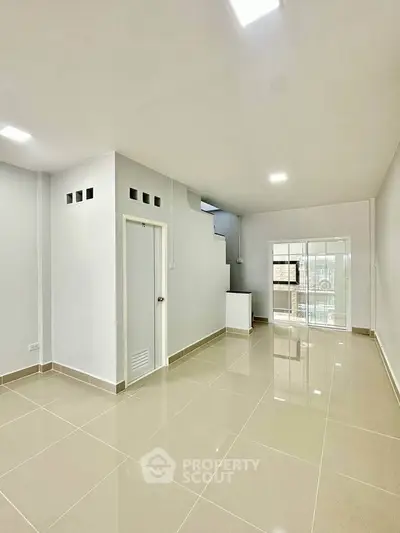 Spacious modern living room with glossy tiled floors and bright natural light.