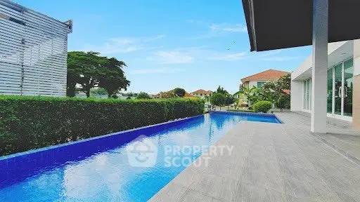 Luxurious modern property with sleek pool and lush greenery, perfect for relaxation and entertainment.