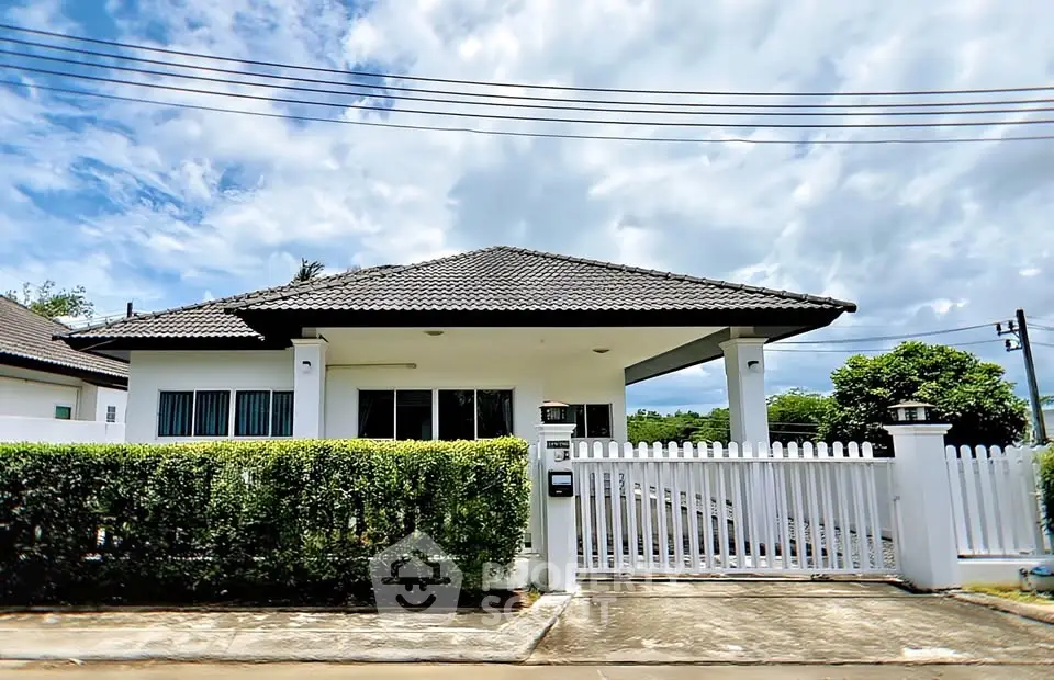 Charming single-story house with white picket fence and lush greenery