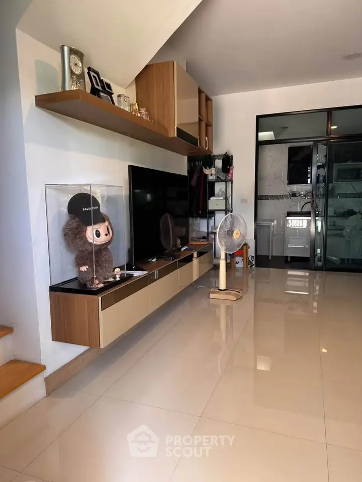 Modern living room with sleek TV unit and glass display case, featuring polished tile flooring.