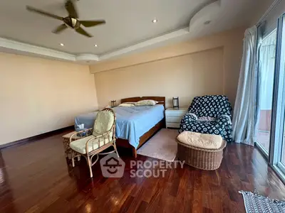 Spacious bedroom with elegant wooden flooring and cozy seating area
