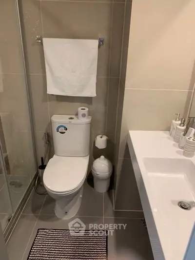 Modern bathroom with shower, toilet, and sleek vanity in neutral tones.