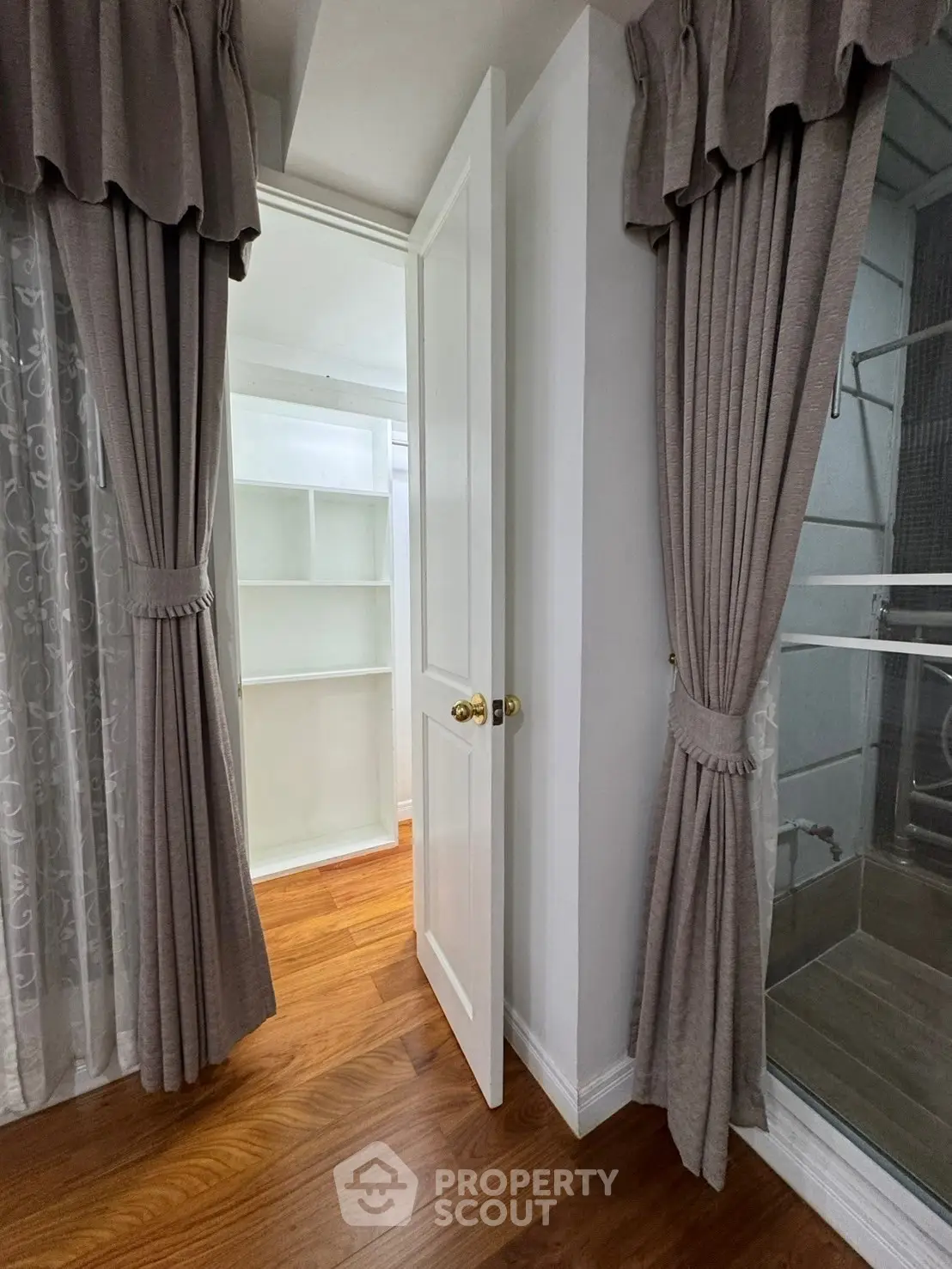Spacious walk-in closet with elegant curtains and wooden flooring