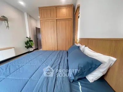 Spacious bedroom with modern wooden wardrobe and cozy blue bedding, perfect for relaxation.