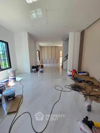 Spacious modern living room under renovation with glossy tile flooring and large windows