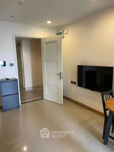 Modern living room with wall-mounted TV and open door leading to hallway
