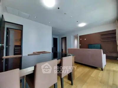 Spacious modern living room with elegant dining area and sleek wooden flooring.