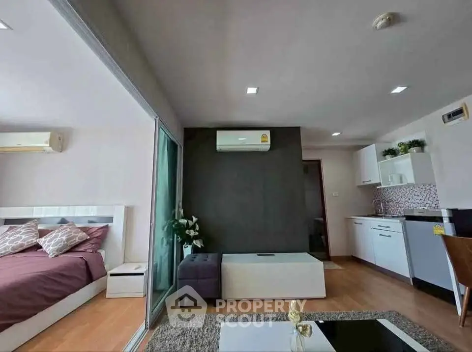 Modern open-plan living room with adjacent bedroom and sleek kitchen design.