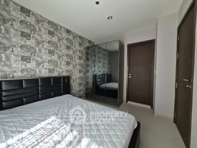Modern bedroom with stylish wallpaper and mirrored wardrobe in a cozy apartment.