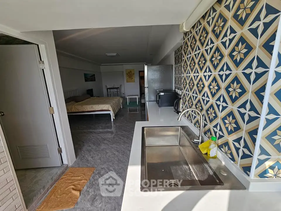Stylish open-layout kitchen with modern sink and patterned backsplash in a cozy apartment.
