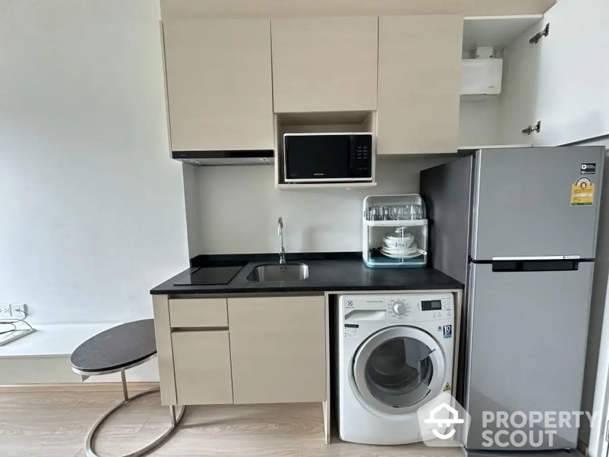 Modern compact kitchen with washing machine and microwave in stylish apartment