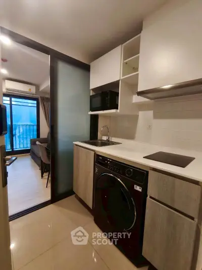 Modern kitchen with sleek appliances and open layout leading to cozy living room.