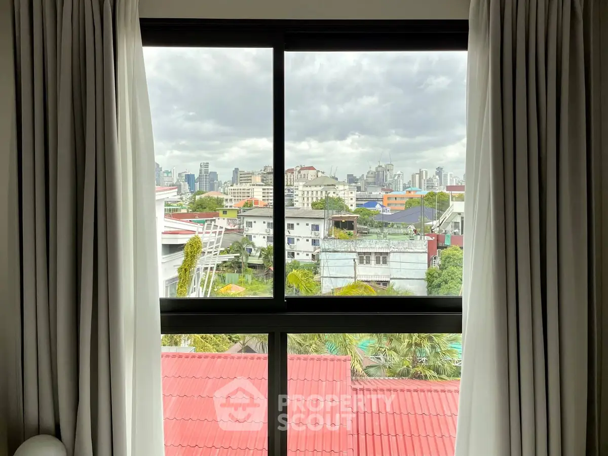 Stunning cityscape view from a modern apartment window with white curtains.
