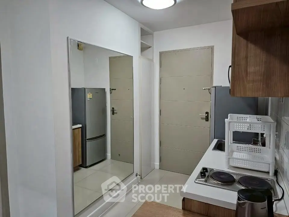 Modern kitchen with sleek appliances and large mirror enhancing space