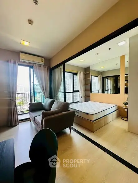 Modern studio apartment with cozy living area and large windows offering city views.