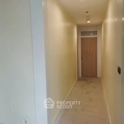 Spacious hallway with wooden door and bright lighting in modern apartment