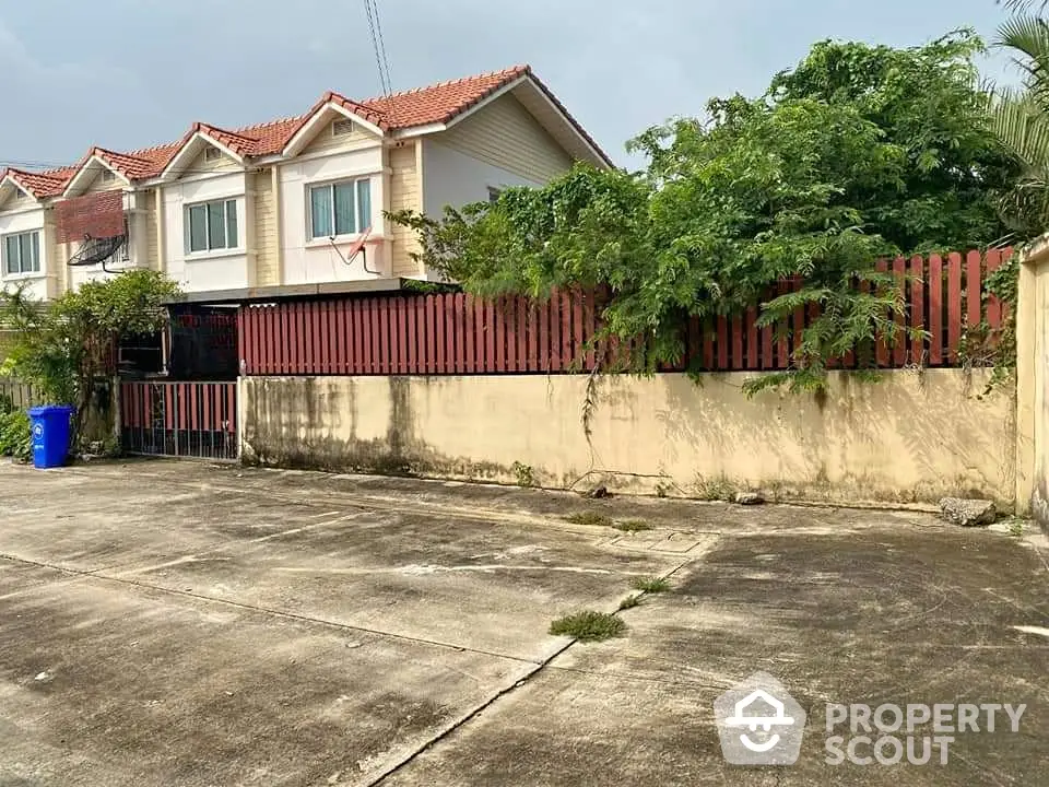 Charming suburban townhouse with red-tiled roof and lush greenery, perfect for families seeking tranquility.