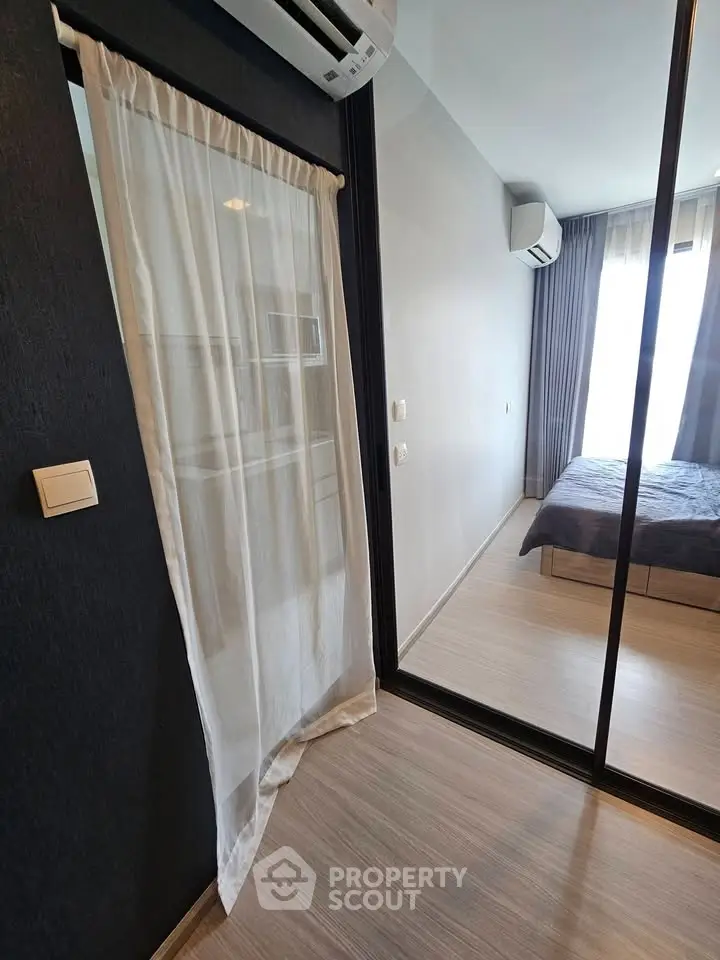 Modern bedroom with glass partition and air conditioning, featuring sleek design and natural light.