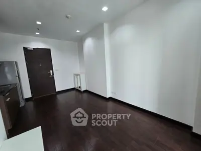 Spacious modern apartment with sleek dark wood flooring and minimalist kitchen.