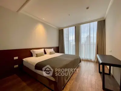 Spacious bedroom with large windows and modern decor in a luxury apartment.