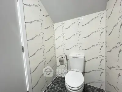 Modern bathroom with stylish marble-patterned walls and geometric floor tiles.
