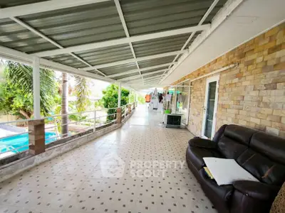 Spacious covered balcony with pool view and comfortable seating area.