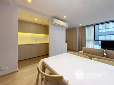 Modern open-plan living room with sleek kitchen and dining area in a stylish apartment.