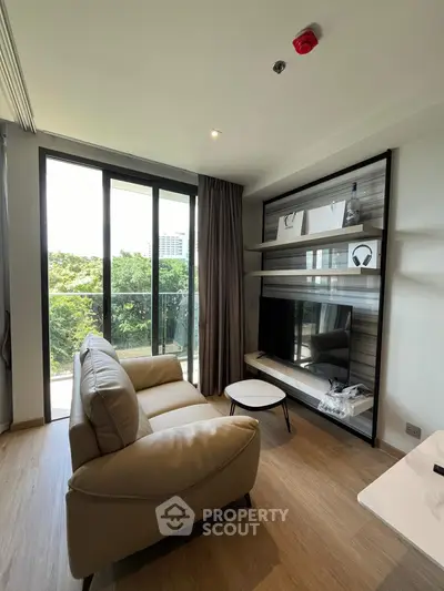 Modern living room with large windows and balcony view, featuring sleek furniture and stylish decor.
