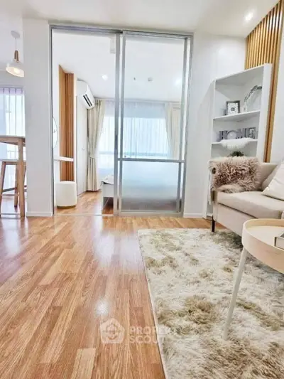 Modern living room with cozy decor and wooden flooring, featuring a glimpse into a stylish bedroom.