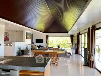 Luxurious open-plan living room with high ceilings and modern decor, featuring expansive windows and elegant furnishings.