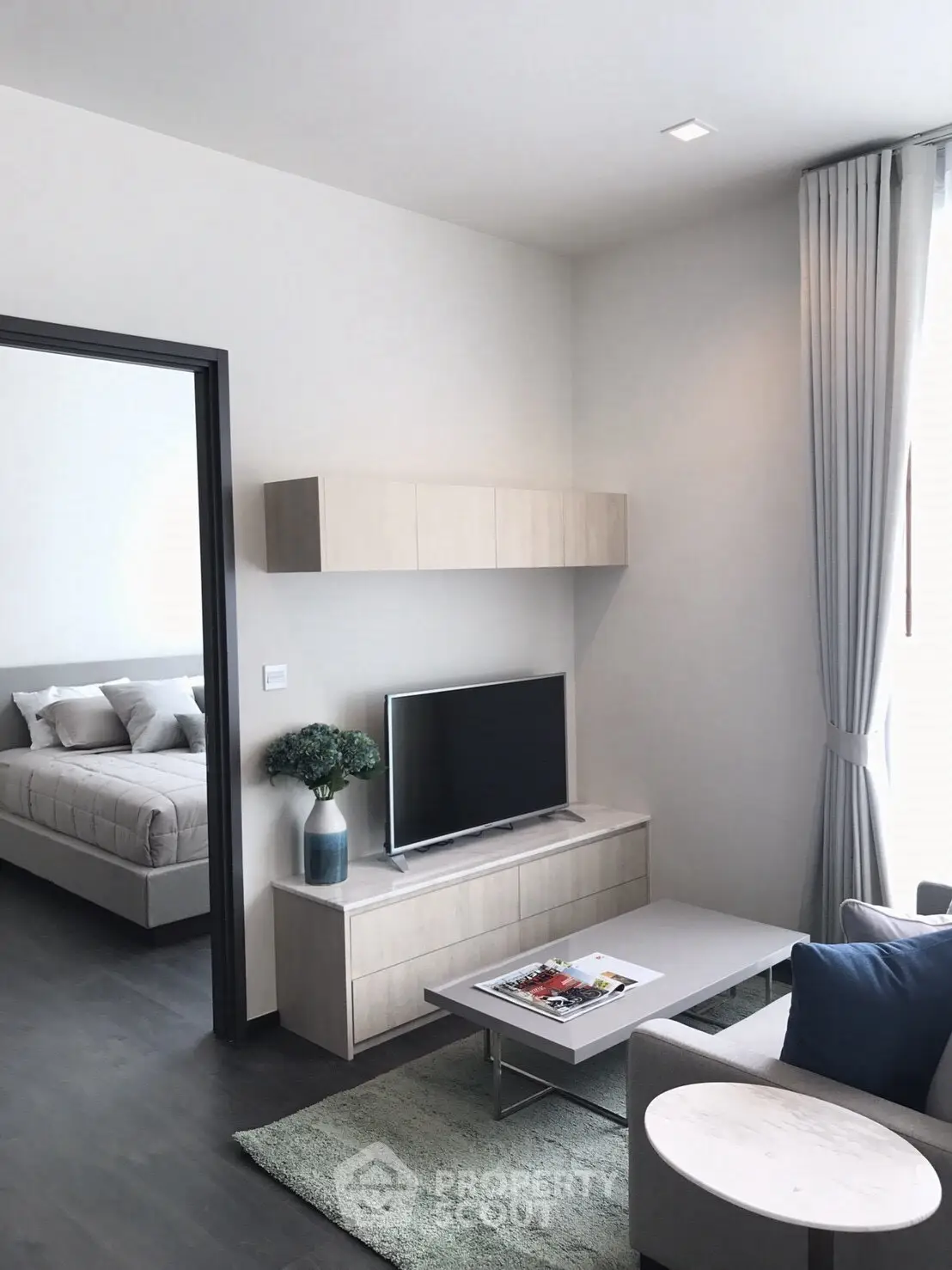 Modern living room with sleek furniture and natural light, featuring a cozy bedroom view.