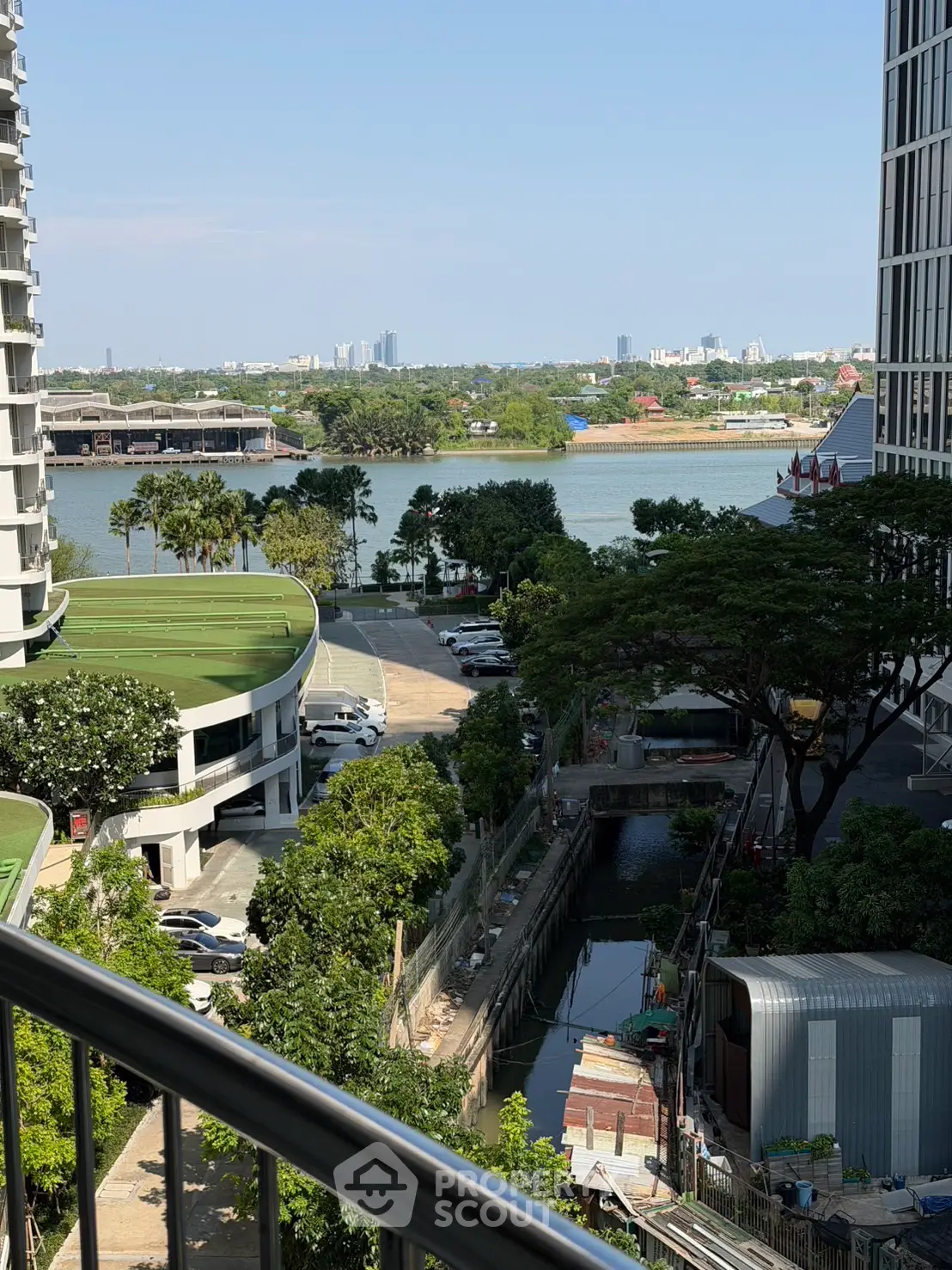 Stunning river view from high-rise balcony with lush greenery and cityscape in the background.