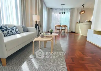 Spacious living room with elegant decor and natural light, featuring a cozy seating area and stylish parquet flooring.