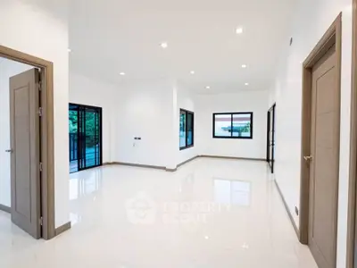Spacious modern living room with large windows and sleek flooring, perfect for natural light and open living.