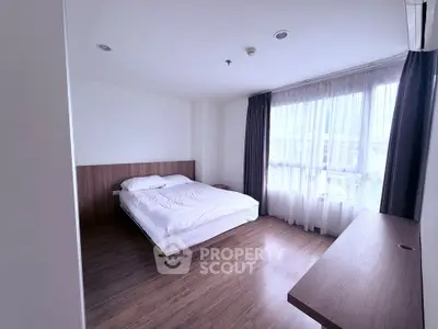 Spacious bedroom with large window and modern wooden flooring