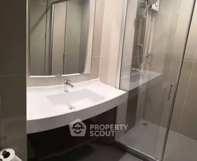 Modern bathroom with sleek sink and glass shower enclosure in contemporary design.