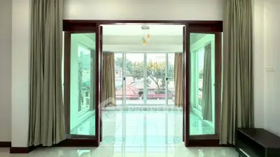 Spacious living room with large windows and elegant curtains, offering a bright and airy atmosphere.