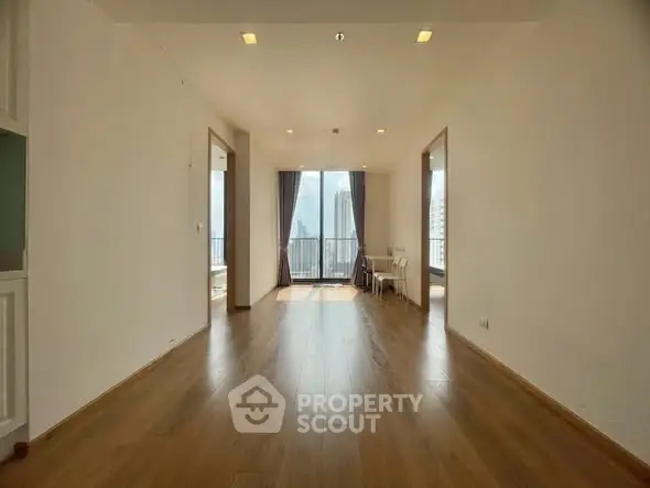 Spacious living room with wooden flooring and city view balcony in modern apartment.
