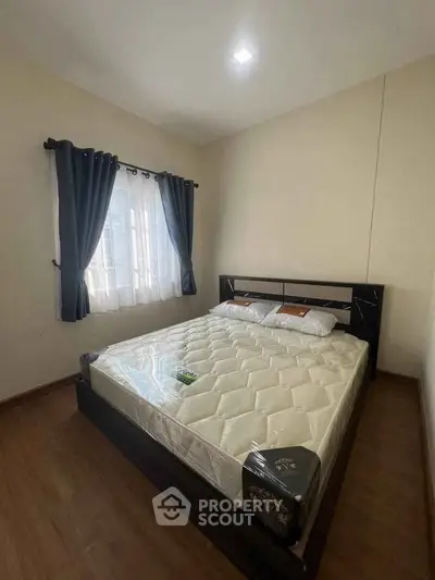 Cozy bedroom with wooden flooring and natural light from window
