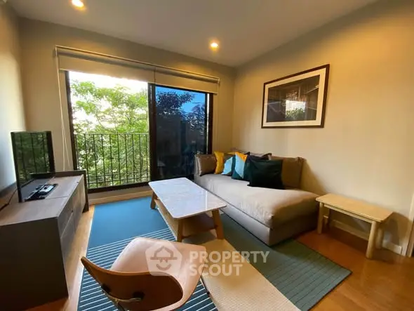 Cozy living room with modern decor and large window offering lush green views.