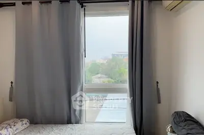 Cozy bedroom with large window and gray curtains offering a serene view.