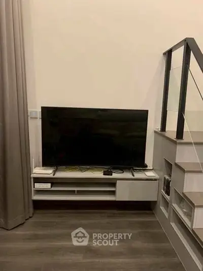 Modern living room with sleek TV setup and stylish staircase