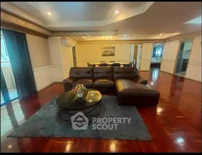 Spacious living room with elegant leather sofa and polished wooden floors in luxury apartment.