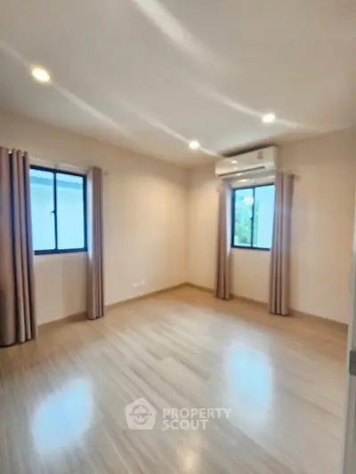 Spacious empty room with wooden flooring and air conditioning, perfect for customization.
