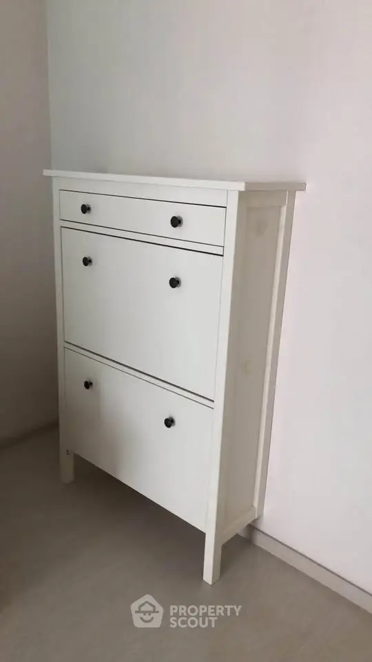 Modern white storage cabinet with sleek design in minimalist interior setting.